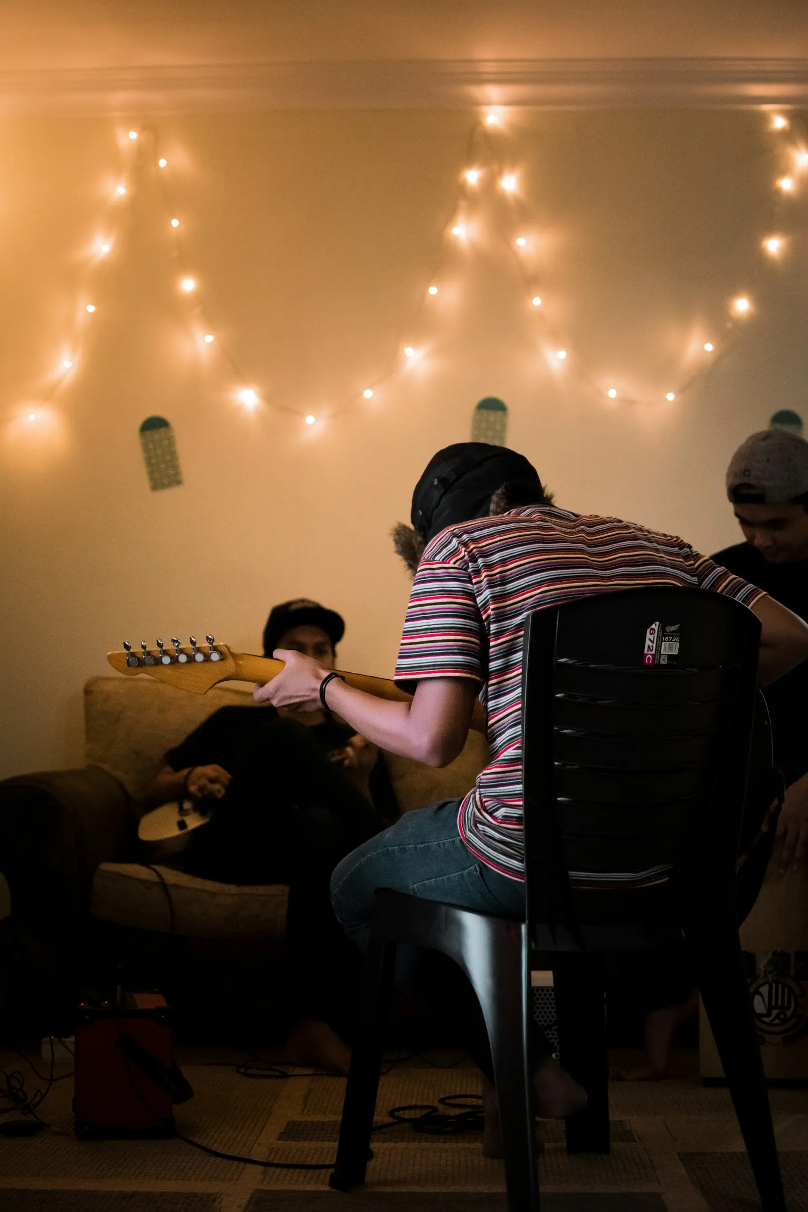 Friends playing music together under string lights in Kuala Lumpur